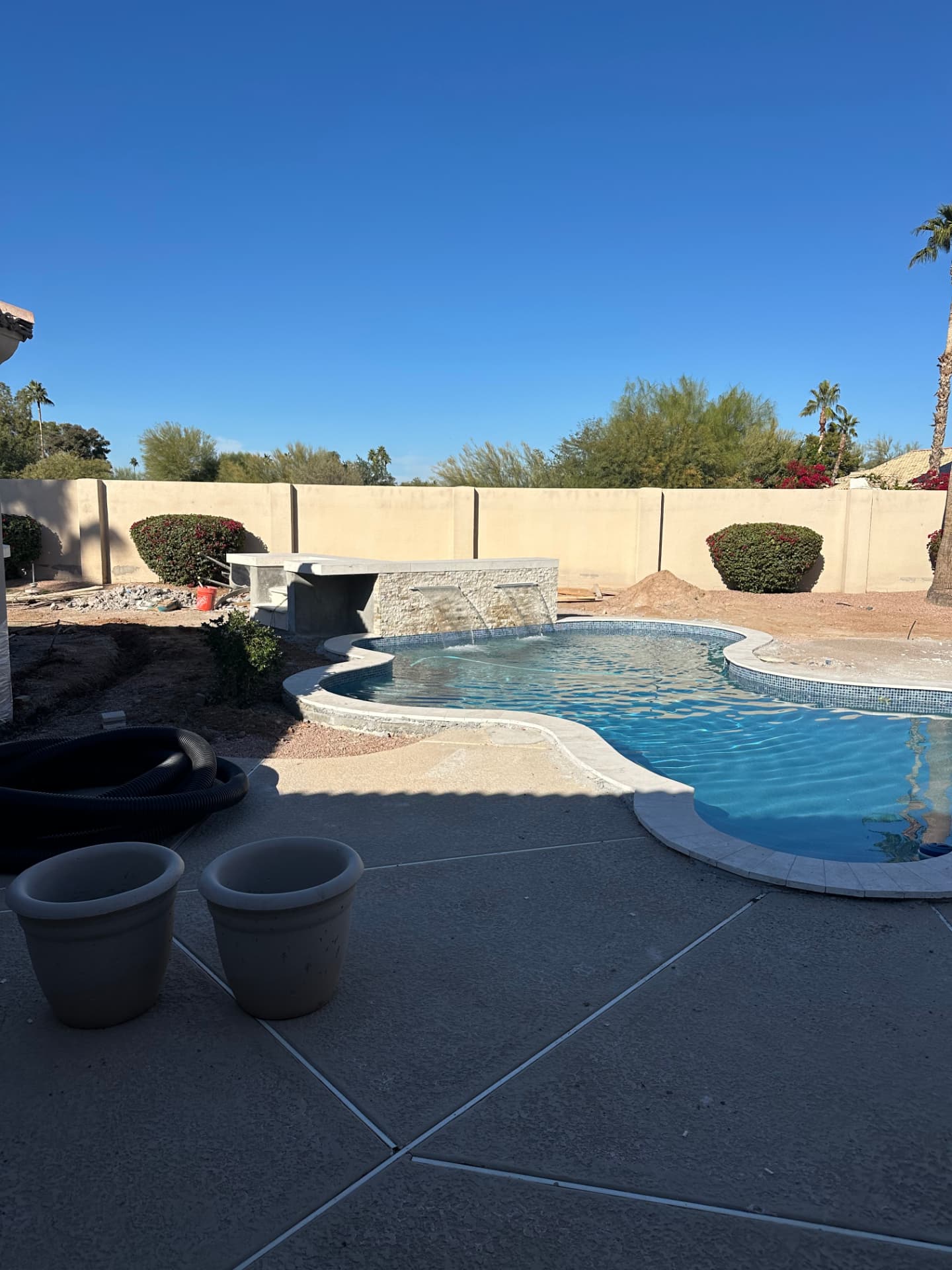 Raised stacked-stone water feature wall taking shape behind the pool