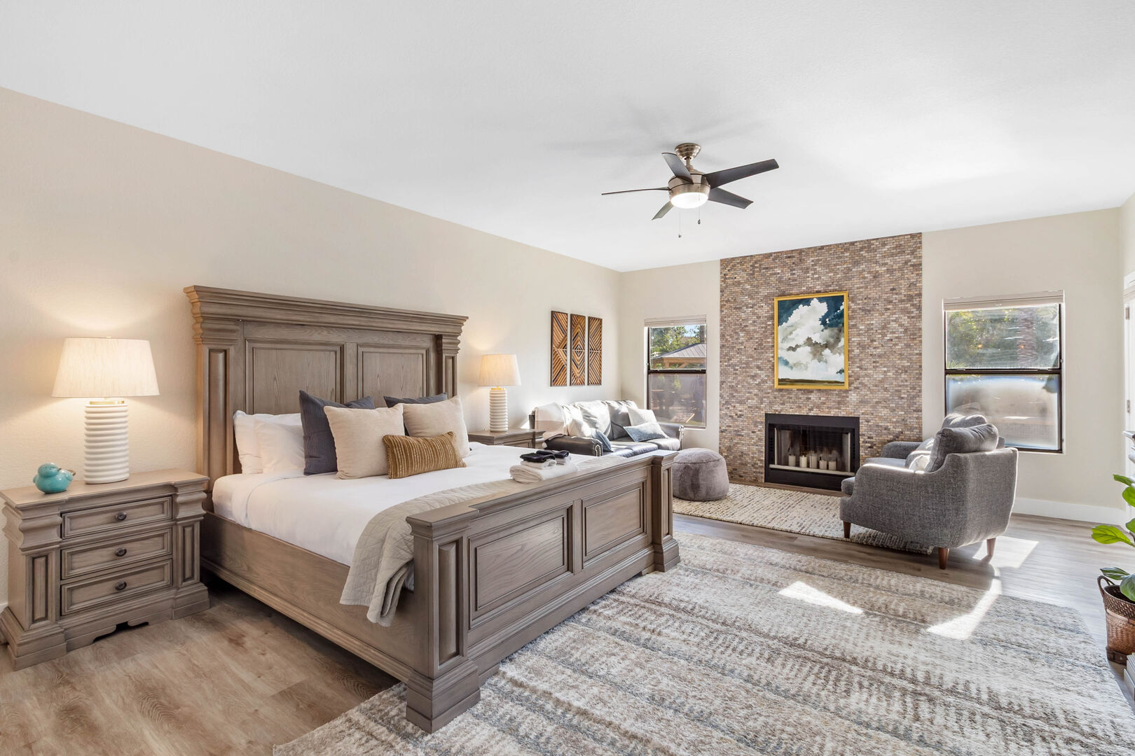 Primary bedroom with king bed, sitting area and brick-tiled fireplace