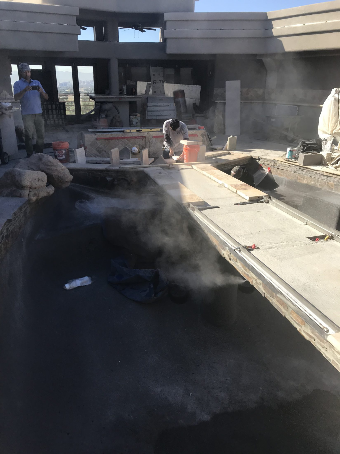 Tile and stacked stonework being set along the pond edge