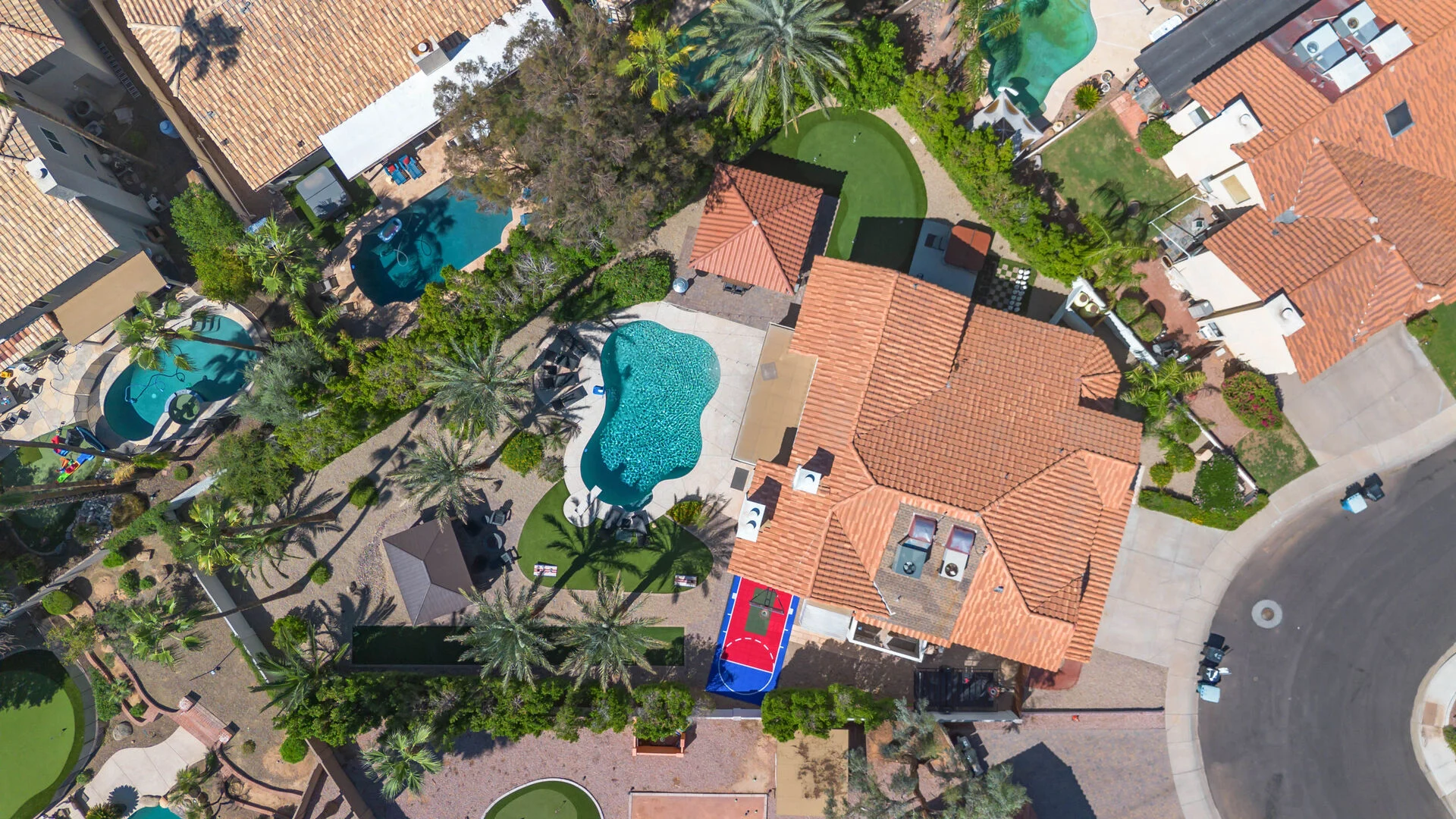 Overhead aerial view of the remodeled home, pool, sport court and putting green