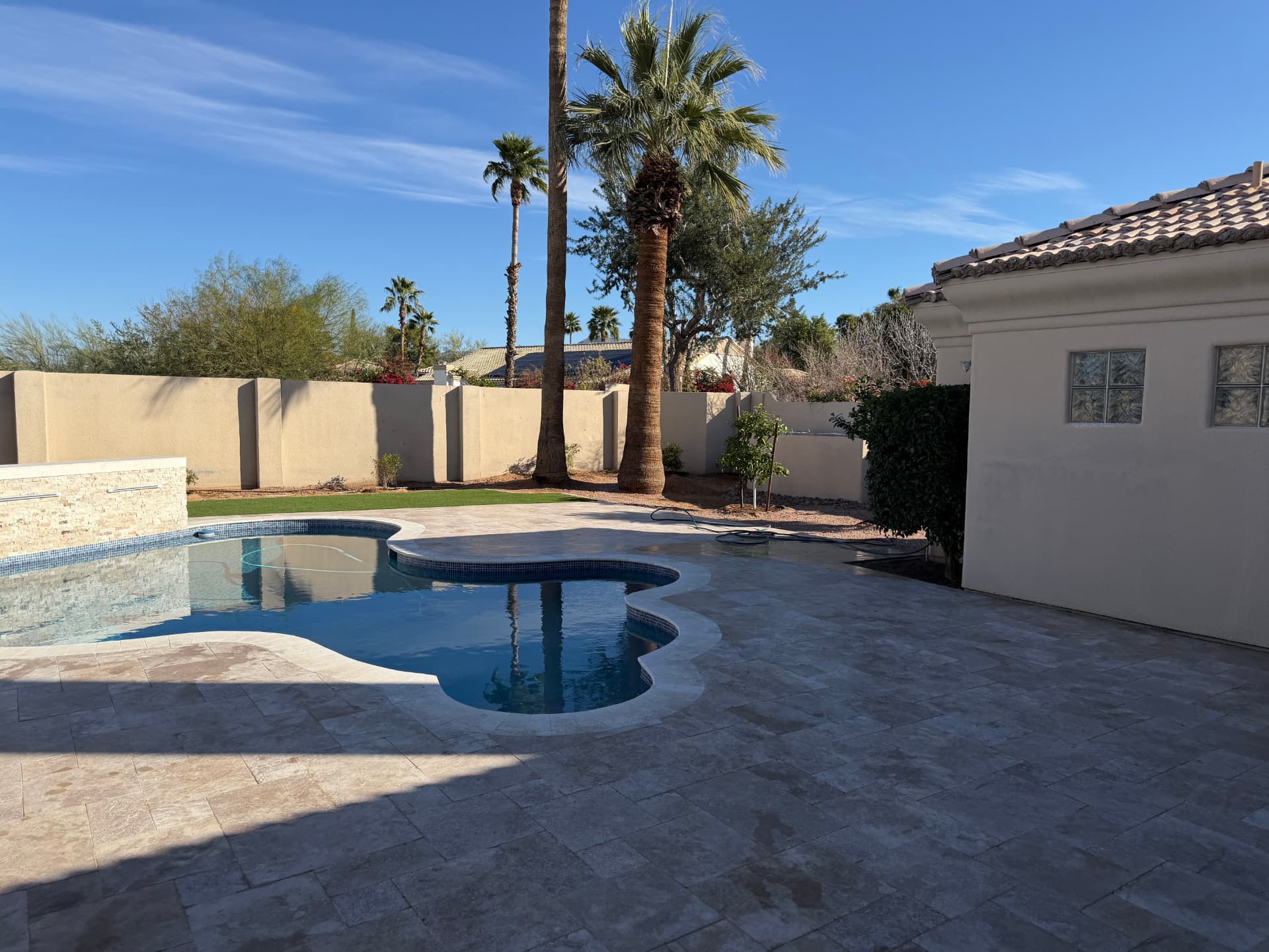 Completed resort-style backyard retreat with pool and travertine deck