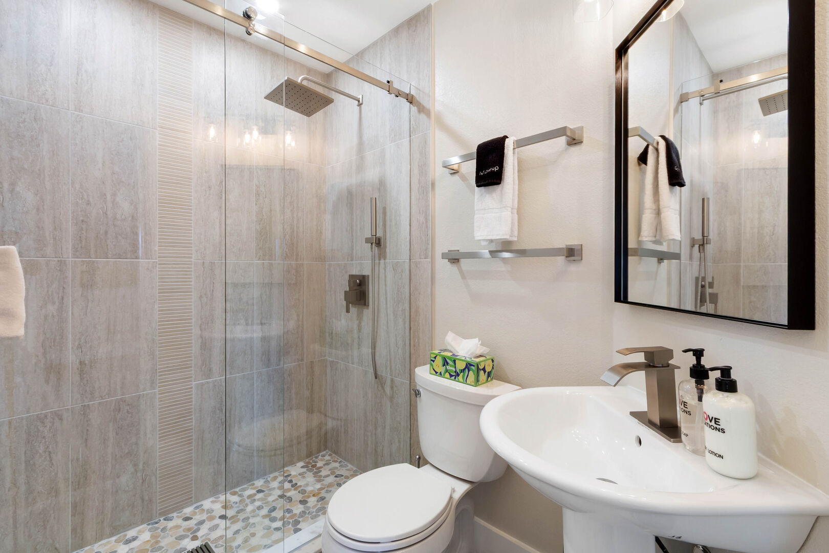 Guest bathroom walk-in shower with large-format tile, pebble floor and rainhead