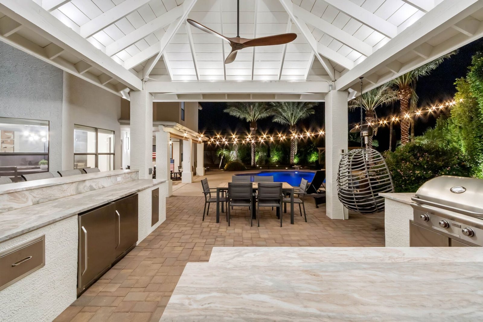 Covered outdoor kitchen and dining pavilion lit at night