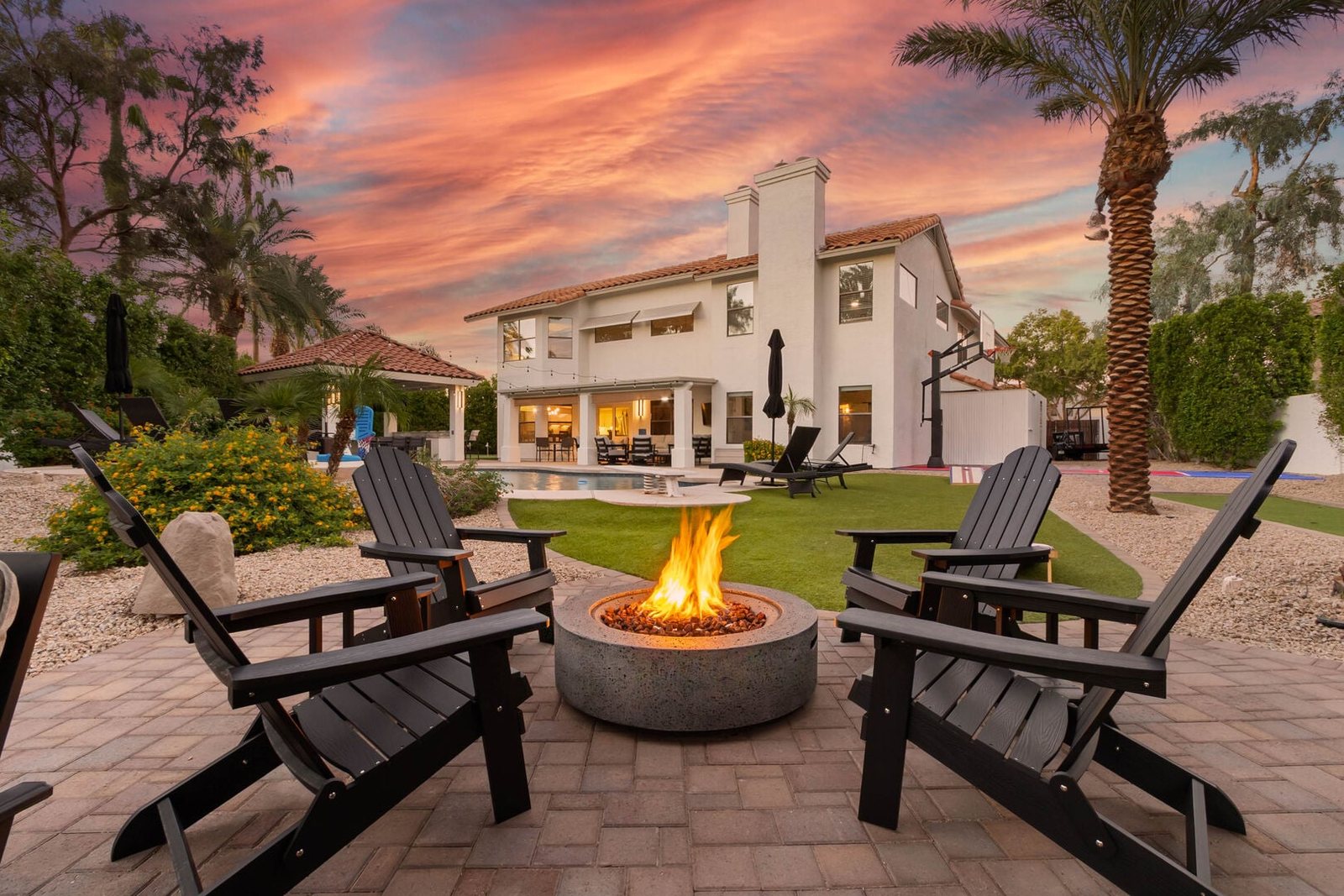 Remodeled Scottsdale backyard at sunset with a gas fire pit, lounge chairs and pavilion