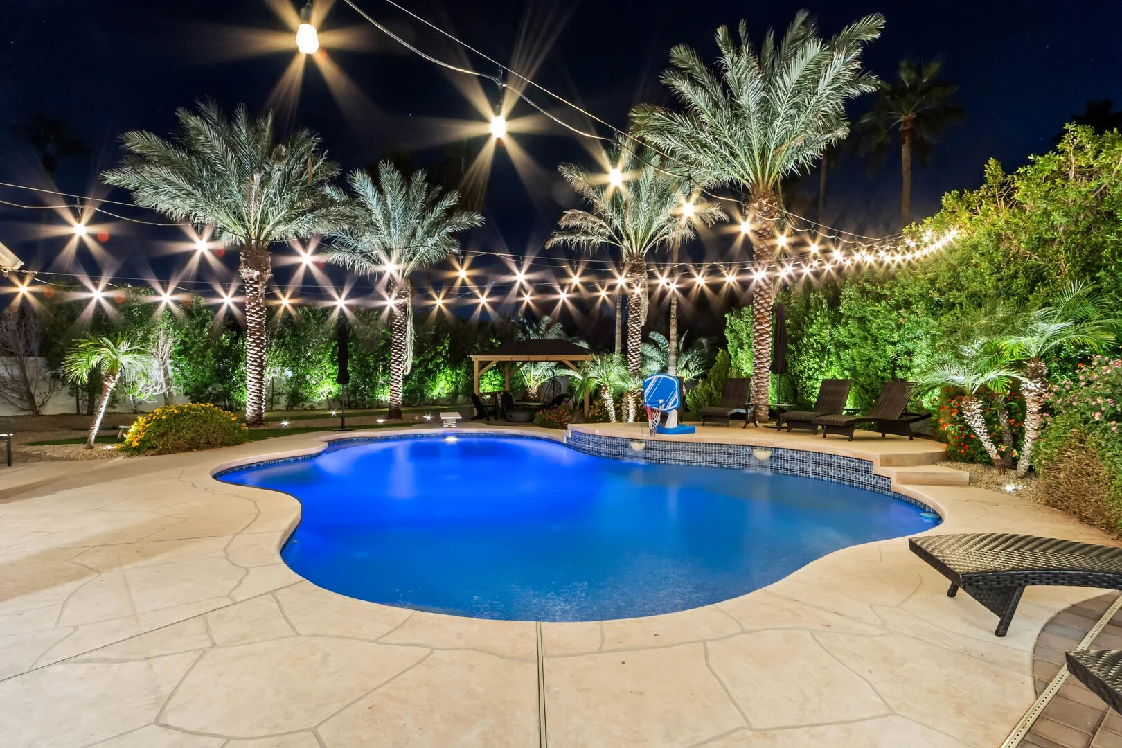 Resort-style backyard pool with string lights and palm trees in the Phoenix Valley