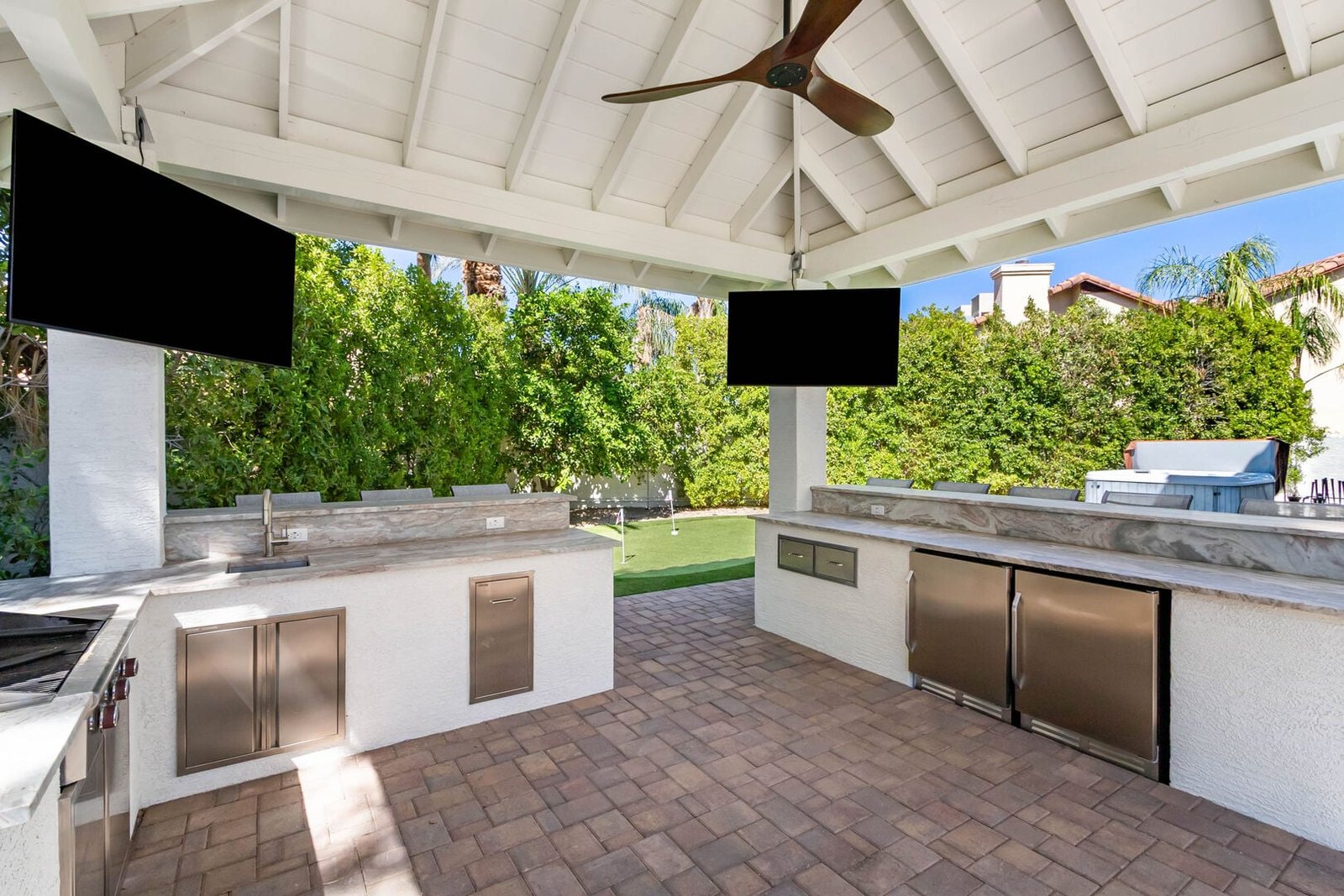 Custom outdoor kitchen with stone bar seating, built-in grill and refrigeration