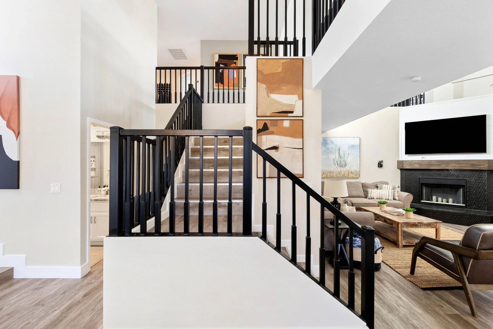 Staircase with black metal railing and wood treads opening to the living room and fireplace