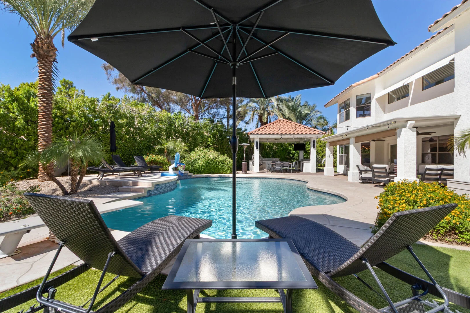 Daytime view of the remodeled pool with new decking, artificial turf and shaded loungers