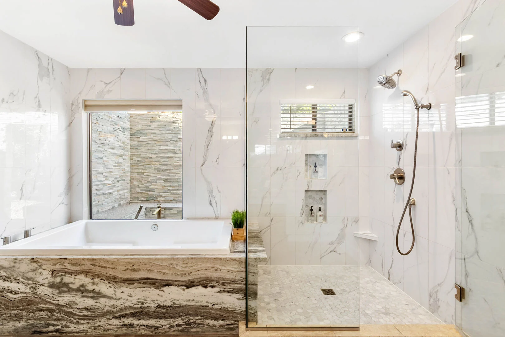 Primary bathroom with marble-look tile, drop-in soaking tub and glass curbless shower