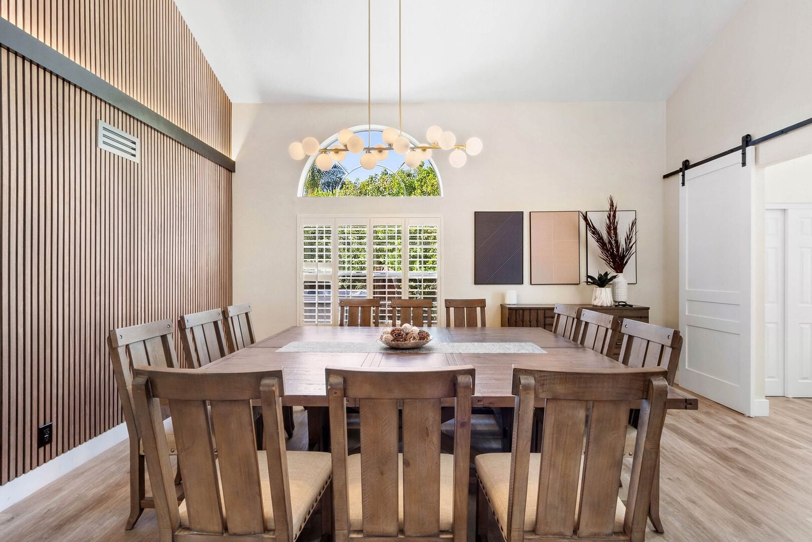 Dining room with vaulted ceiling, custom wood slat feature wall and long dining table