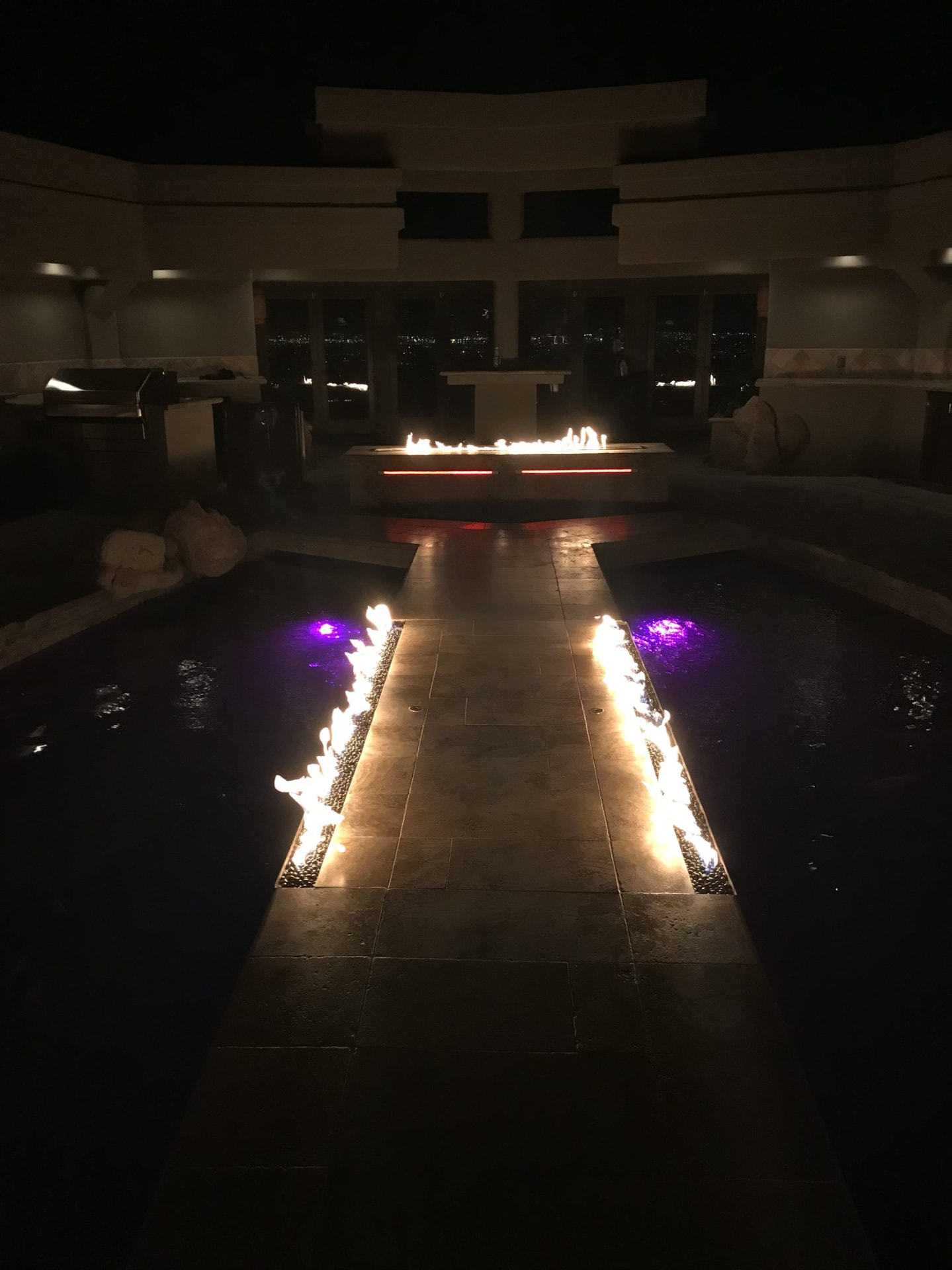 The koi pond walkway after dark with fire features and colored lighting